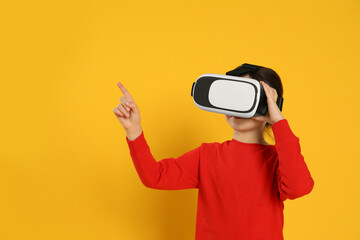 Little girl using virtual reality headset on yellow background