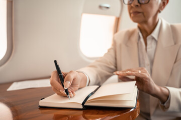 Cropped view of blurred businesswoman writing on notebook in private jet