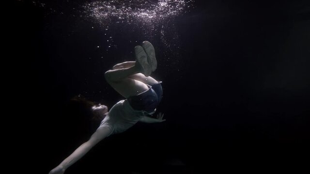 slow motion underwater a woman in clothes floats as if in space