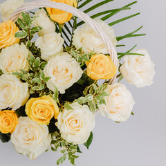 Flower arrangement in basket with white, yellow and pistachio roses.