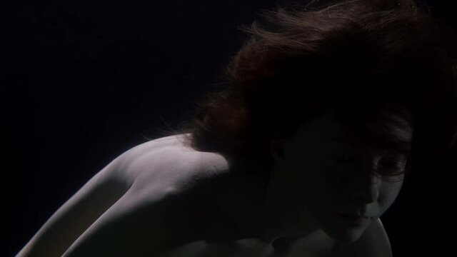 slow motion underwater portrait of a woman nude unconscious as in a dream floating in zero gravity