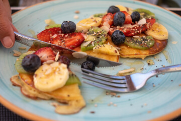 Close-up on healthy summer breakfast, classic american pancakes with banana, kiwi, fresh berry and honey
