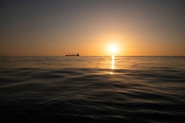 Silhouette of a freight ship on the horizon of the Mediterranean sea during sunset