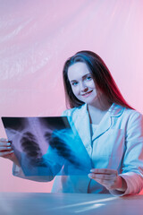 Diagnostic X-ray. Lung checkup. Medical expertise. Healthcare specialist. Cheerful smiling female doctor examining chest radiograph film on pink.