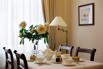 table setting a table in the living room set for tea with flowers in front of the window