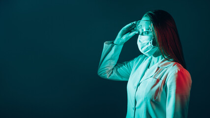 Lab experiment. Medical innovation. Microbiology research. Shocked curious female doctor in face mask white coat taking off goggles isolated on teal blue empty space background.