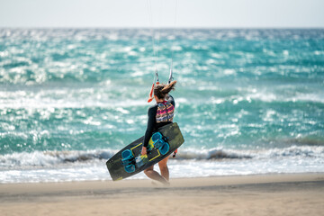 Young woman kitesurfer on the beach entering the sea with her board. Sotavento beach in Fuerteventura