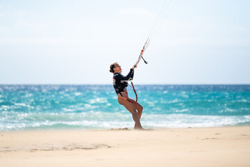 Young female kitesurfer on the beach looking at her kite. Sotavento beach in Fuerteventura