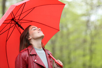 Woman breathing under red umbrella in a park