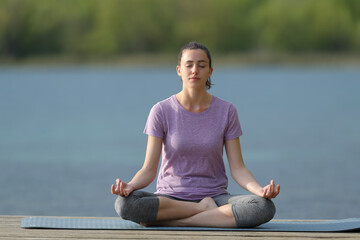 Fototapeta na wymiar Woman doing yoga lotus pose in a lake
