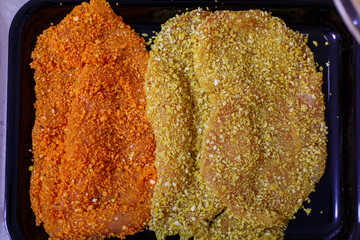 Petto di pollo pronto per essere fritto panato con pangrattato grosso condito e colorato a mano con una marinata rossa per la carne