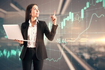 Successful investing concept with happy trader woman with laptop on virtual screen background with growing financial chart graphs and candlestick.