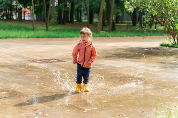 child playing in a puddle after rain