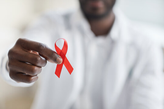Close-up of male doctor holding red ribbon