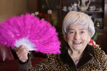 Senior woman holding plumy pink feather hand fan