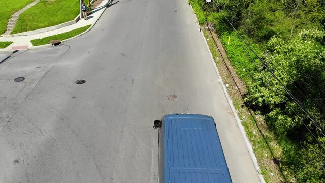 Amazon vans drive down a city street, aerial drone