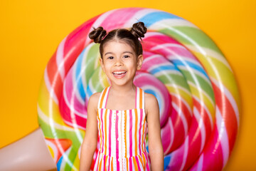 Happy excited arab child girl in colorful striped dress having fun on yellow background with...