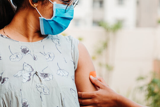 Closeup shot of hand applying bandage to the arm of an Indian teen girl after taking the vaccine for coronavirus pandemic. girl wearing mask