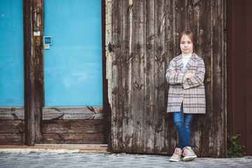 Portrait of adorable little fashionable girl outdoors near old fence