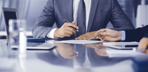 Unknown business people working together at meeting in modern office, close-up. Businessman and woman with colleagues or lawyers discussing contract at negotiation