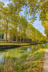 Beautiful autumn views of Canal du Midi (in XVII century - Royal Canal in Languedoc) in Toulouse and trees reflection in water. Toulouse, Haute-Garonne, France.