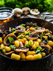 Gnocchi with fried white mushrooms on wooden table
