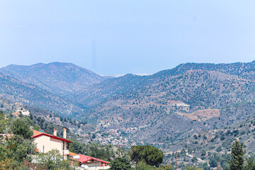 Obraz premium Roofs of Kykkos monastery between green trees on a clear sunny day