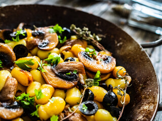 Gnocchi with fried white mushrooms on wooden table
