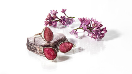 Silver earrings and ring with dark pink rubies on a white background with reflection.  Isolated...