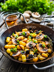 Gnocchi with fried white mushrooms on wooden table
