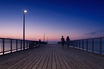 PIER ON THE SEA COAST - Womens walk at a quiet sunset