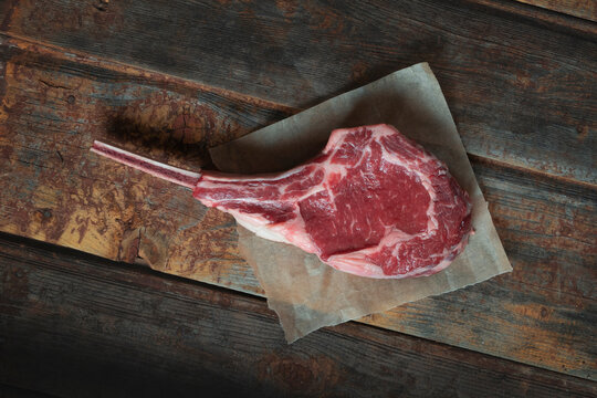Raw tomahawk steak on a wooden background. Top view