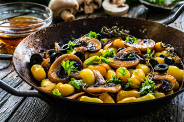 Gnocchi with fried white mushrooms on wooden table
