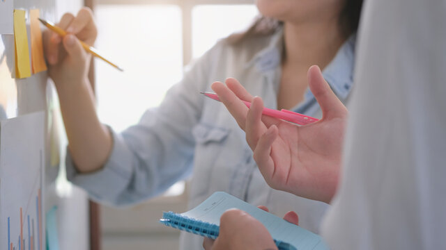 Asian business man hand holding note paper meeting with new startup project use post it notes to share idea discussion and analysis data charts and graphs.Business finances and accounting concept