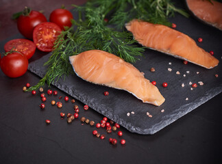 Fresh fish. piece of raw salmon fish fillet, spices on a black stone surface, Delicious fish meat. top view. Healthy food.