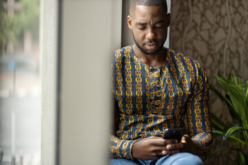 Portrait traditional black African entrepreneur smiling, typing phone