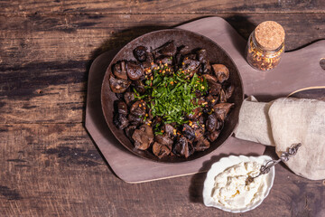 Fried royal champignons in an old cast-iron skillet with trendy hard light, dark shadow