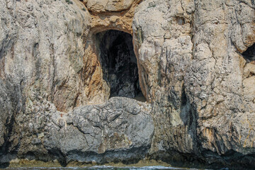 Large cave entrances in a stone cliff above the sea in Cyprus