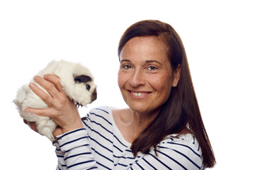 Happy loving woman holding up her pet guinea pig in her hands turning to look at the camera with a friendly smile isolated on white