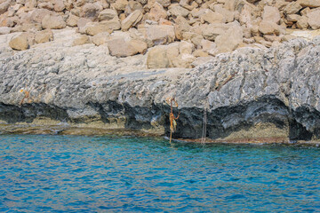 Small backwater surrounded by a stone cliff with azure water in Cyprus