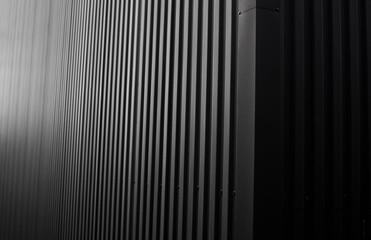 Black corrugated iron sheet used as a facade of a warehouse or factory. Texture of a seamless corrugated zinc sheet metal aluminum facade. Architecture. Metal texture.