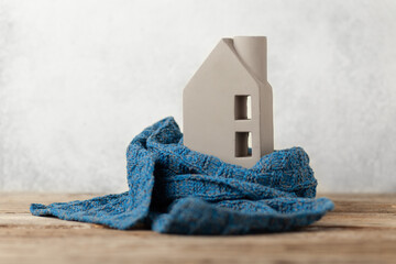 House insulation. Miniature of a house in a knitted scarf to save heat in winter.