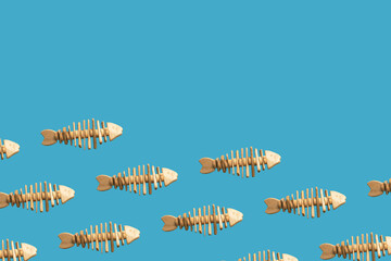 School of fish concept, pattern with toy fishes handmade from old pieces of wood swimming on blue