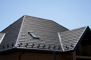 Brown corrugated metal profile roof installed on a modern house with a attic windows. The roof of...