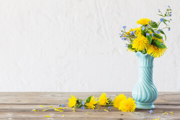 yellow and blue spring flowers s in blue vase on white background