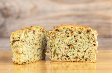 Two halves of a freshly baked muffin with bacon and dill on a cutting board.