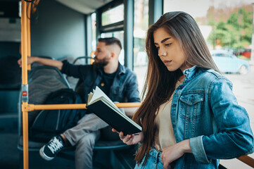 Woman reading a book while standing in a moving bus