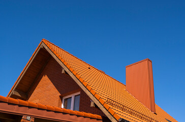 Red corrugated metal profile roof installed on a modern house. The roof of corrugated sheet. Roofing of metal profile wavy shape. Modern roof made of metal. Metal roofing.