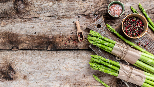 banches of fresh green asparagus on wooden background, Clean eating, dieting, vegan, vegetarian, healthy food concept. Long banner format, top view
