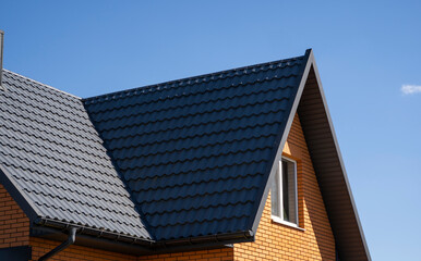 Fototapeta premium Grey corrugated metal profile roof installed on a modern house. The roof of corrugated sheet. Roofing of metal profile wavy shape. Modern roof made of metal. Metal roofing.